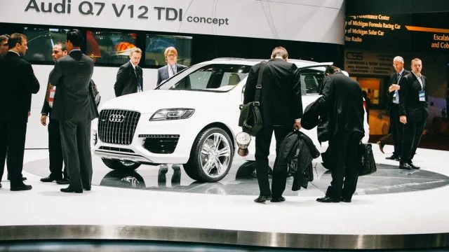 2007: стенд Audi на автосалоне в Детройте, который датируется 1899 годом. Первый неамериканский автопроизводитель прибыл в 1957 году. Немецкие автопроизводители заняли большие стенды и, вероятно, вложили больше, чем они получили от Мичиганских покупателей. 2019: большинство немецких автопроизводителей под залог.