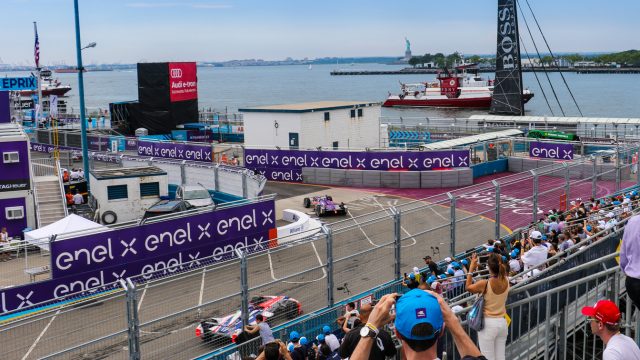 View from the start/finish grandstands: racetrack, boats in New York harbor, Governor&#039;s Island, and Statue of Liberty. Manhattan&#039;s Wall Street is just out of the picture on the right. (Credit: Bill Howard)