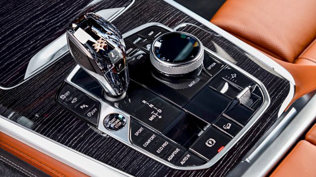 BMW X7 center console: The function selectors forward of the iDrive controller are blocked by the optional crystal shifter, and the button cluster lost its find-by-shape pronounced vee-design.